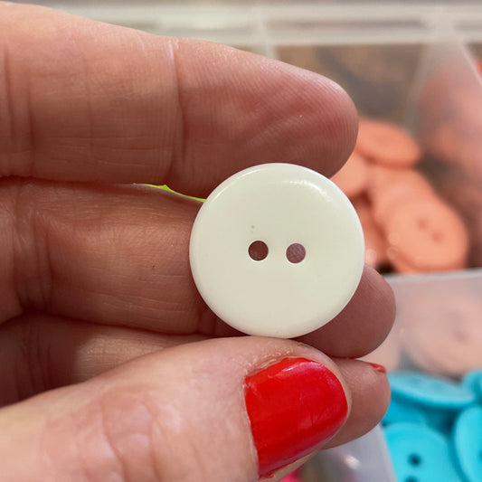 Hand holding a white button with a background of colorful buttons