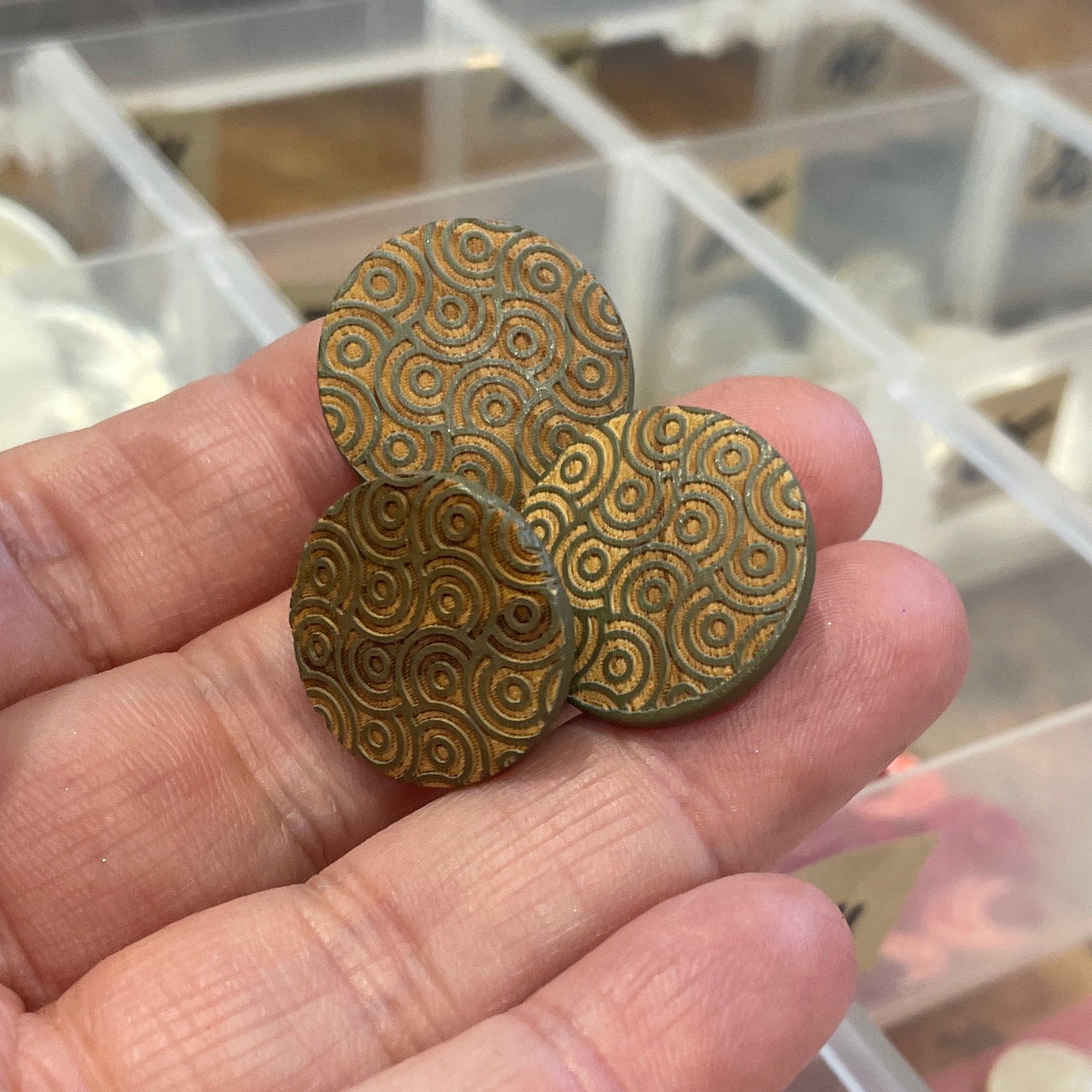 Hand holding buttons with a blurred background of containers.