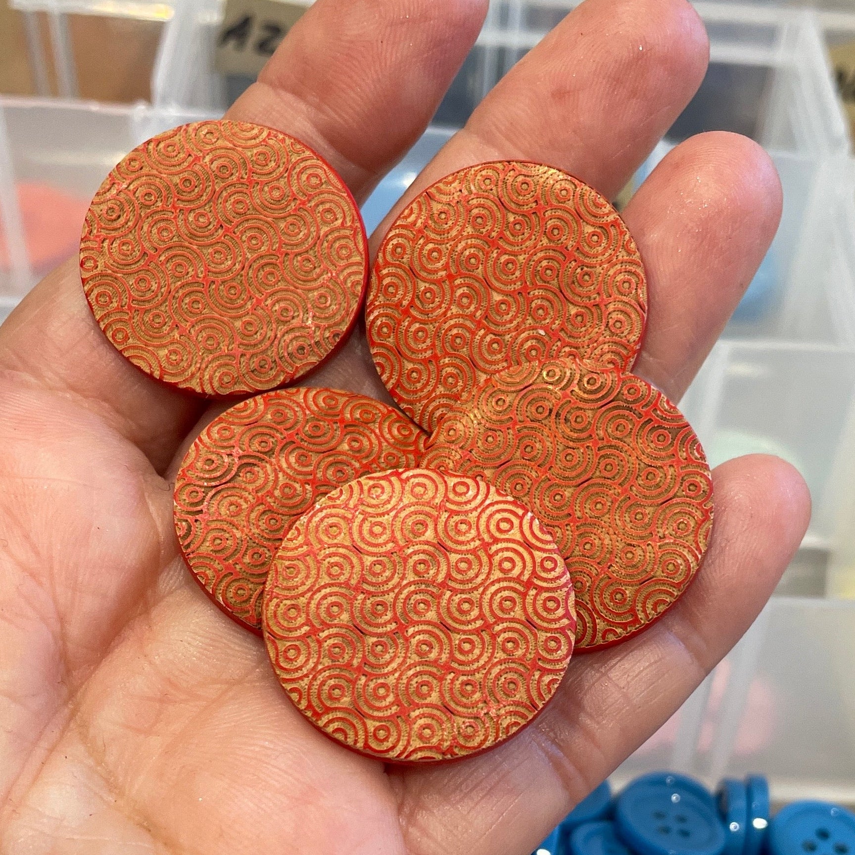 Hand holding buttons with a container of buttons in the background