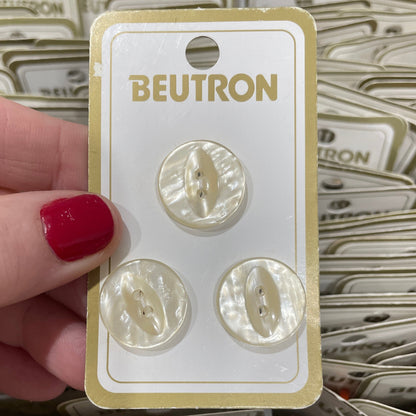 Set of pearl-like buttons on a Beutron card held by a hand with red nail polish.