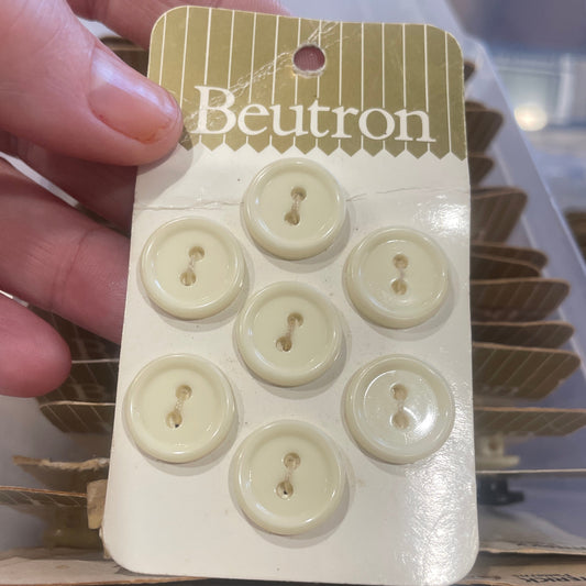 Card with white buttons held by a hand, brand 'Beutron' visible