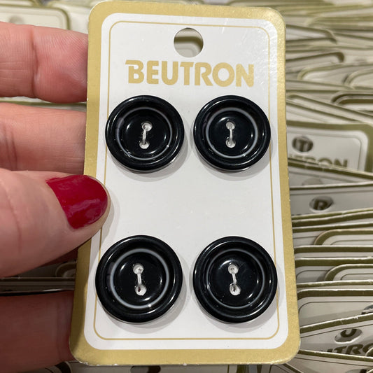 Hand holding a Beutron button with multiple packages in the background.
