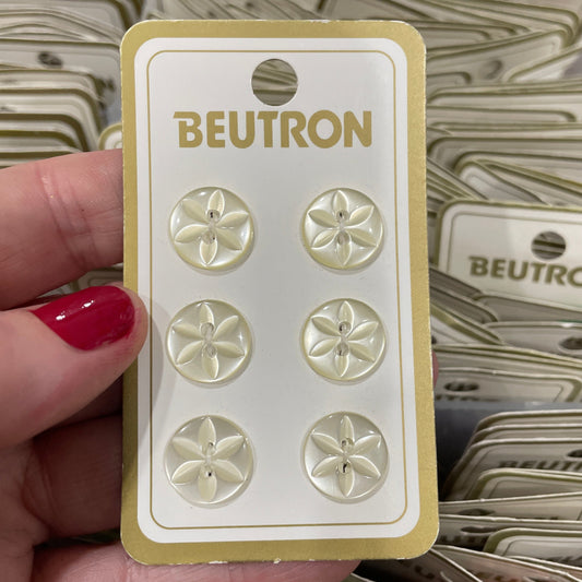 Hand holding a card with buttons labeled 'Beutron' against a blurred background of similar cards.