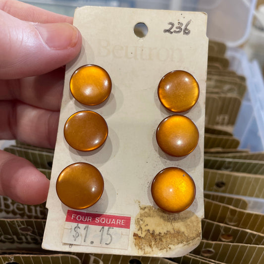 Set of amber-colored buttons on a card held by a hand, with a blurred background