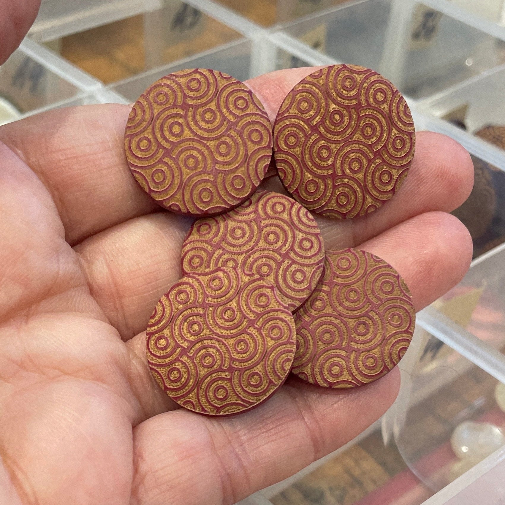 Hand holding wooden buttons with a container of assorted buttons in the background