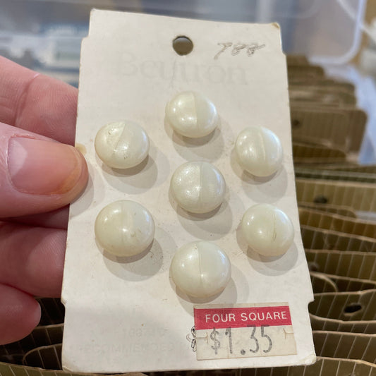 Card with white buttons held by a hand, with a clear container in the background