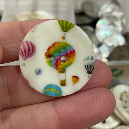 Colorful button held by a hand with a blurred background of more buttons.