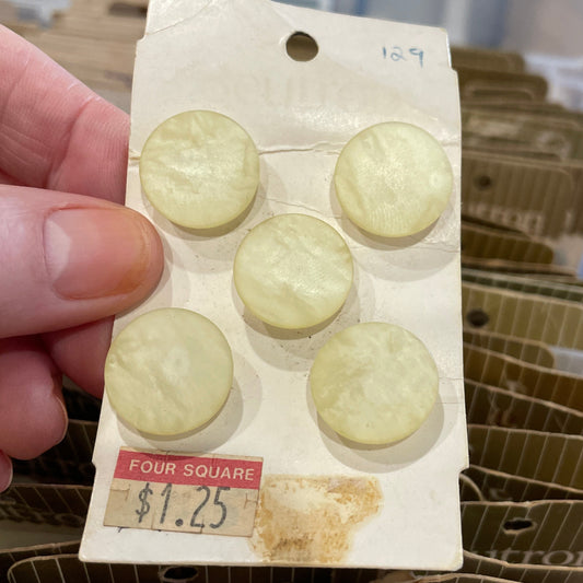 Card with buttons held by a hand, with a clear container of similar cards in the background.