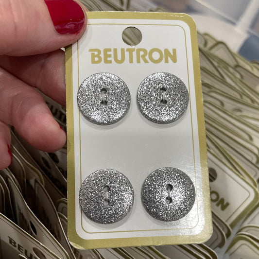 Silver glittery buttons on a BEUTRON card held by a hand.
