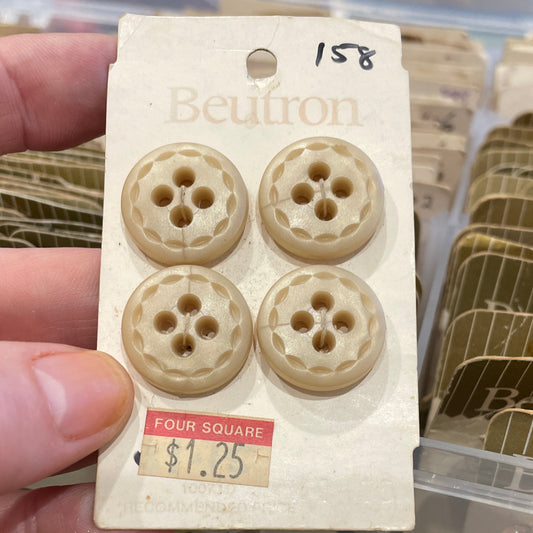 Set of four buttons on a card held by a hand with a blurred background