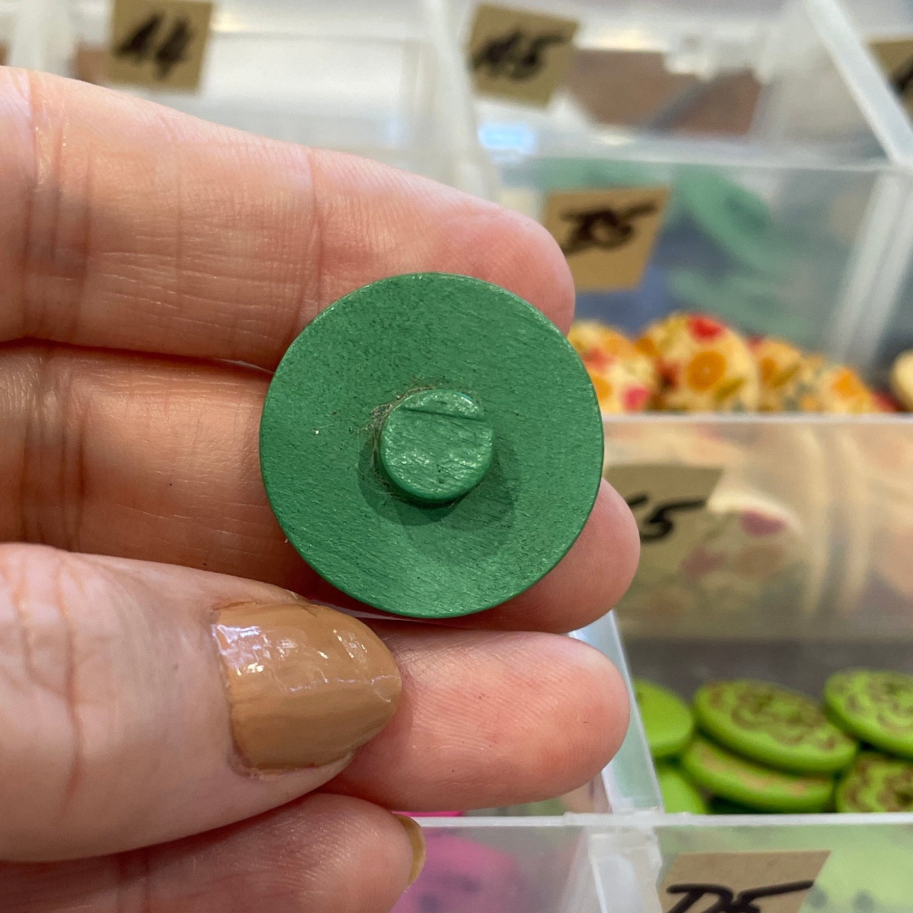 Hand holding a green button with a display of various buttons in the background