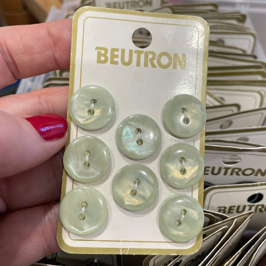 Pack of light green buttons with 'Beutron' branding held by a hand.
