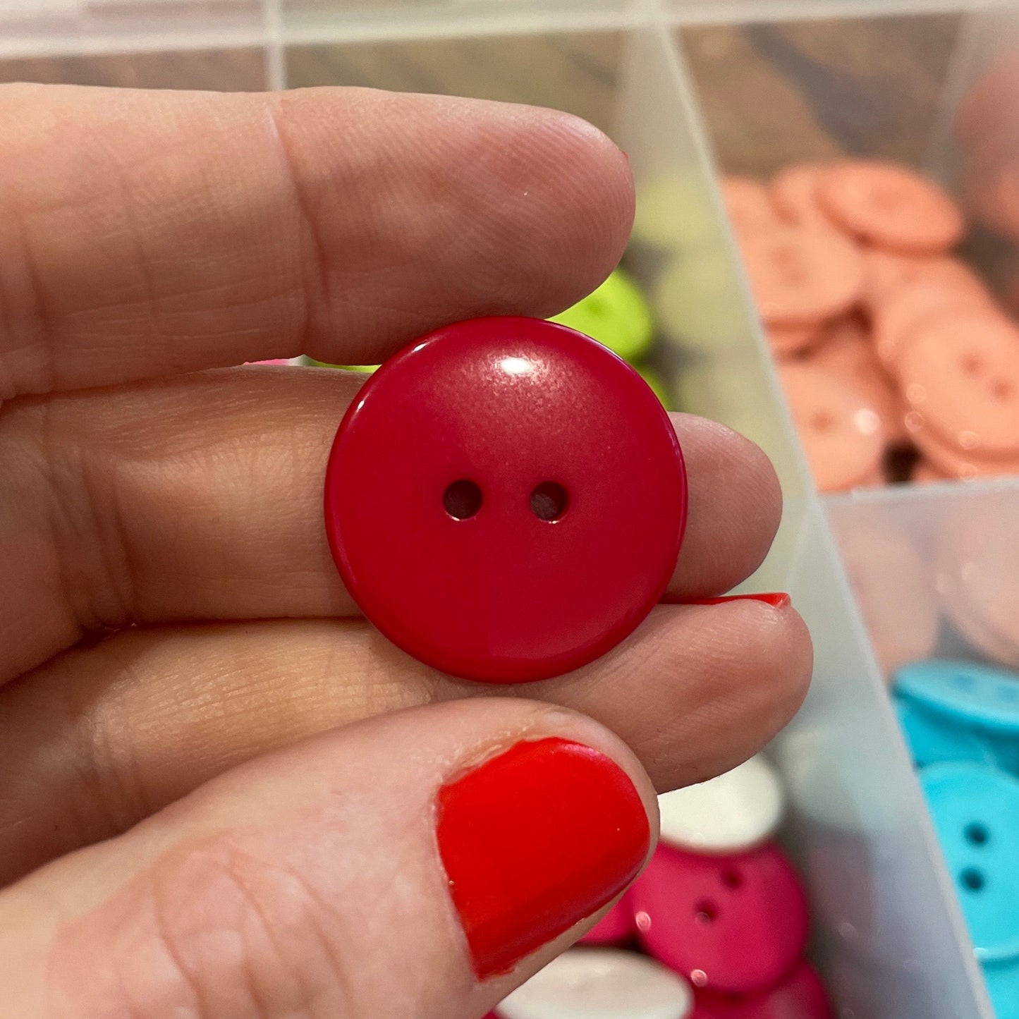 Hand holding a red button with colorful buttons in the background