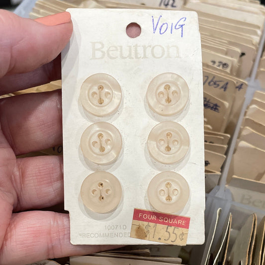 Hand holding a small card with six round buttons, against a background of similar cards.