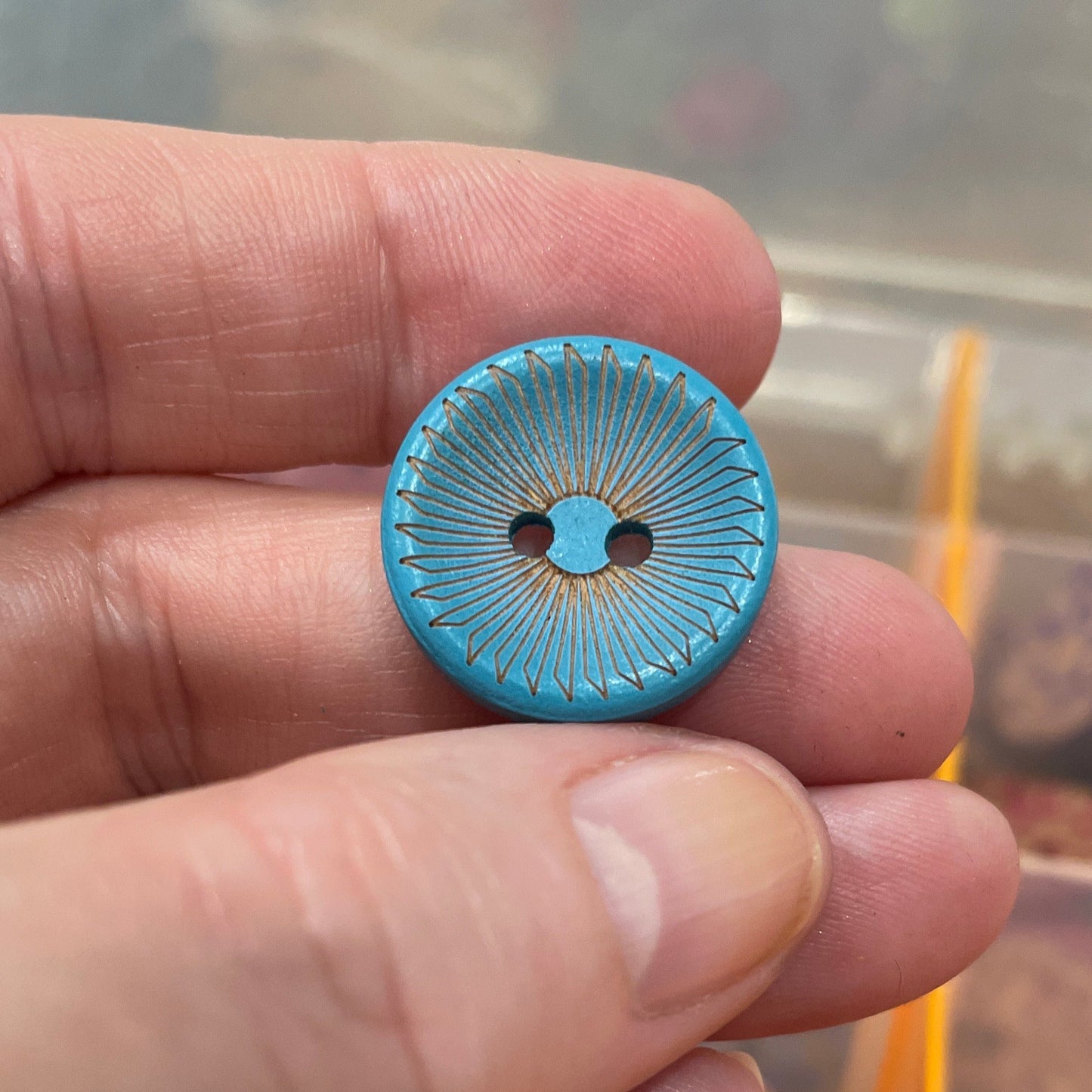 Hand holding a blue button with a blurred background of buttons