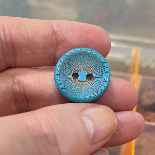Hand holding a blue button with a blurred background of buttons
