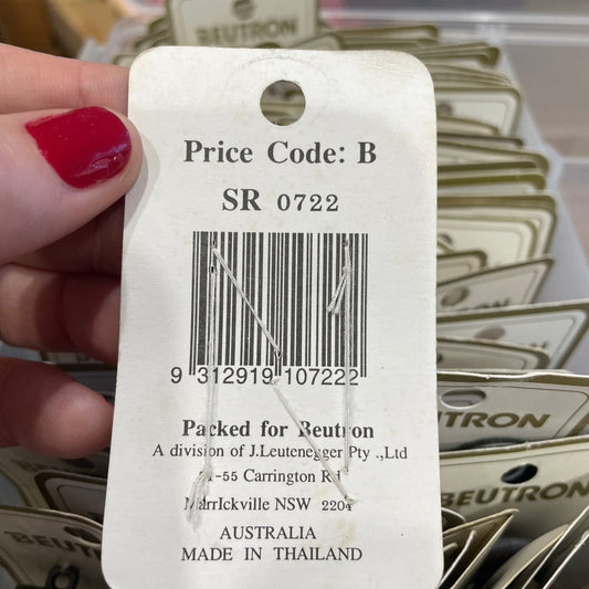 Close-up of a product tag with a barcode, held by a hand with red nail polish.