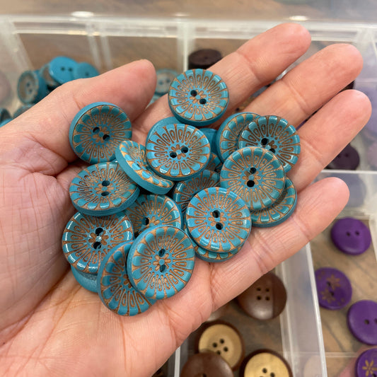 Hand holding blue buttons with a clear container of buttons in the background