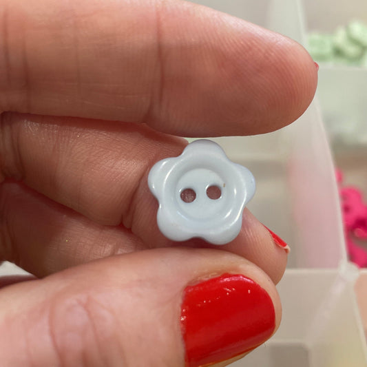 White button held between fingers with a colorful assortment of buttons in the background
