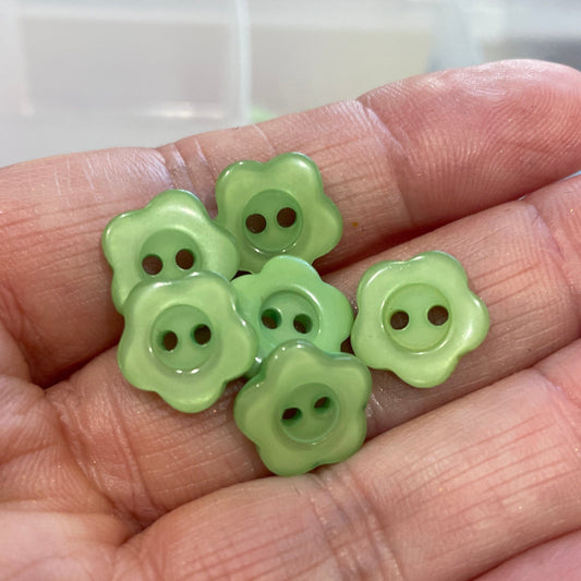 Hand holding green flower-shaped buttons with a blurred background