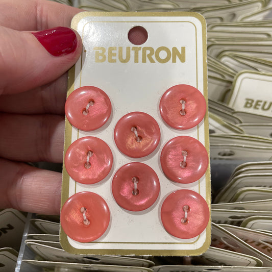 Pack of pink buttons held by a hand with red nail polish, brand 'Beutron' visible