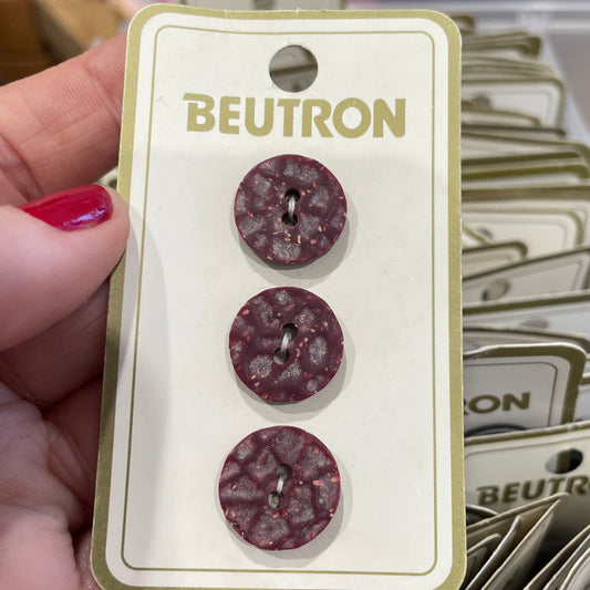 Three buttons on a Beutron branded card held by a hand.