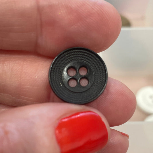Hand holding a black button with a blurred background