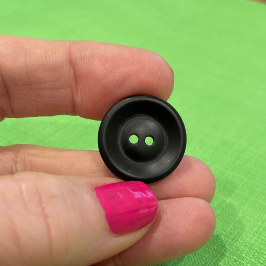 Hand holding a small black button with green light against a green background