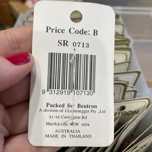 Close-up of a product tag with a barcode and text, held by a hand.