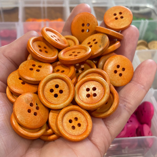 Hand holding a collection of orange buttons with a blurred background