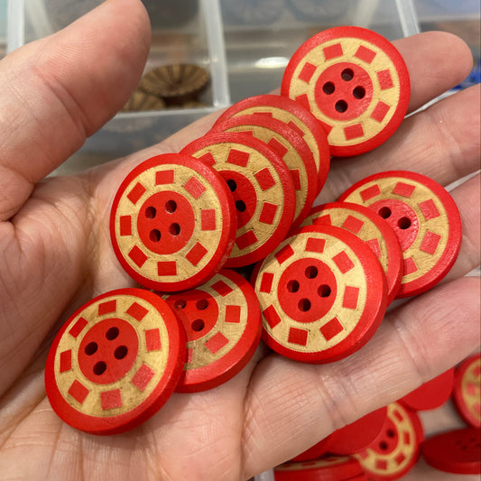 Hand holding red and yellow buttons with a clear container in the background