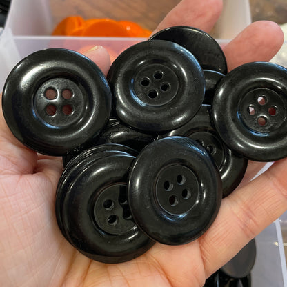 Hand holding a collection of black buttons with a blurred background