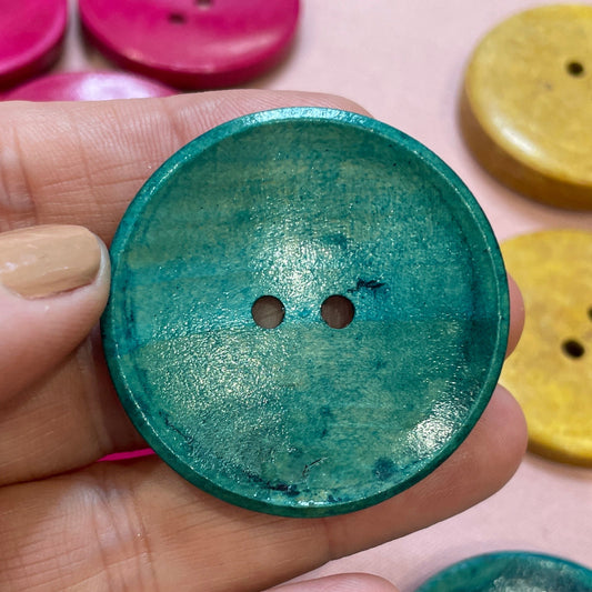 Hand holding a green button with colorful buttons in the background