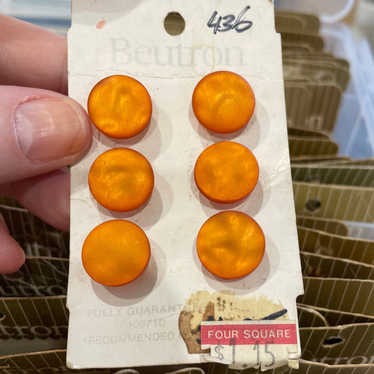 Orange buttons on a card held by a hand with a blurred background