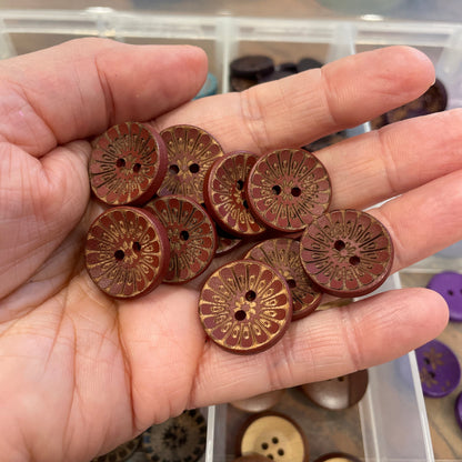 Hand holding wooden buttons with a container of buttons in the background