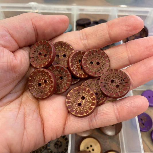 Hand holding wooden buttons with a container of buttons in the background