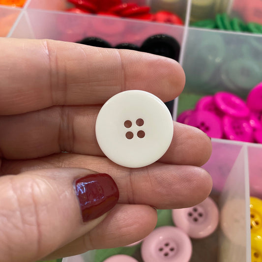 Hand holding a white button with colorful buttons in the background
