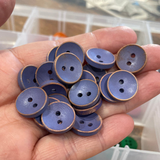 Hand holding purple buttons with a blurred background of more buttons and containers.