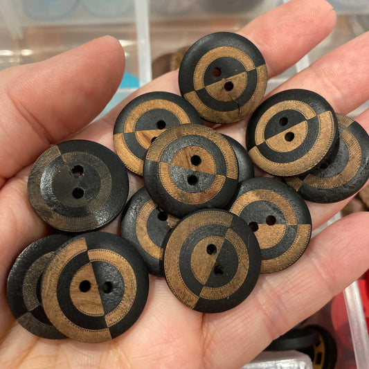 Hand holding a collection of wooden buttons with circular patterns.