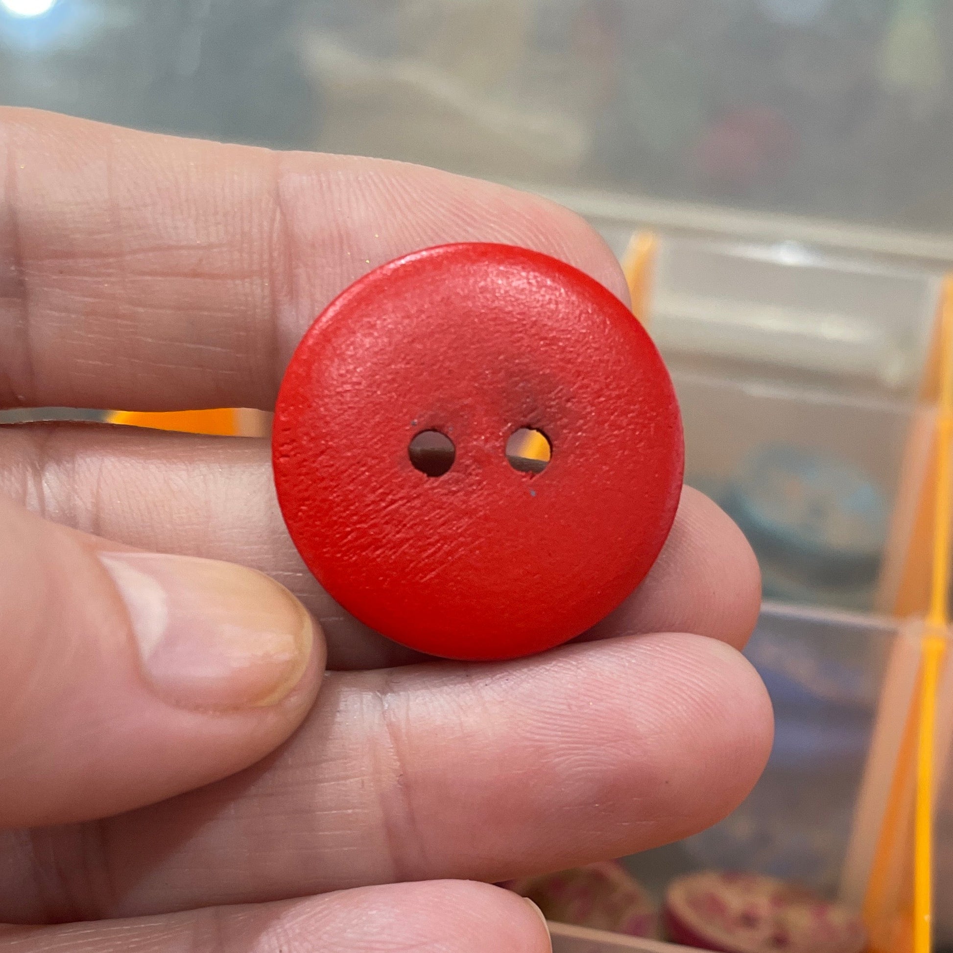 Red button held by a hand with a display of buttons in the background