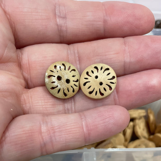 Gold buttons held in a hand with a container of green buttons in the background