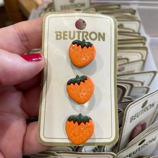 Strawberry-shaped buttons on a BEUTRON card held by a hand with red nail polish.