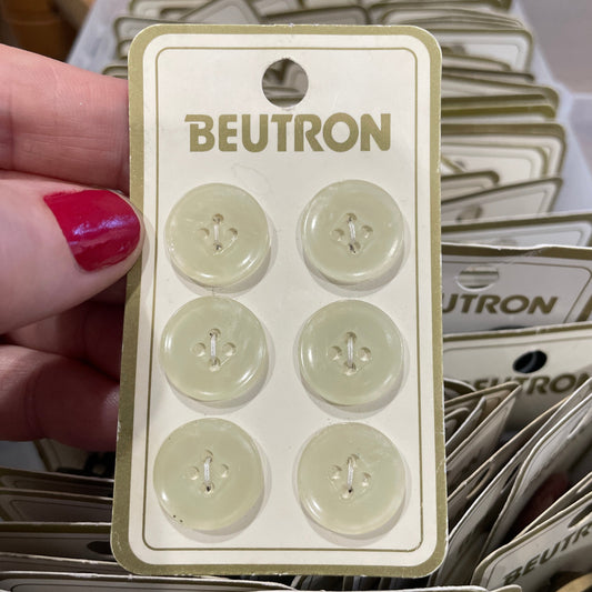 Packaging of BEUTRON buttons held by a hand with red nail polish.