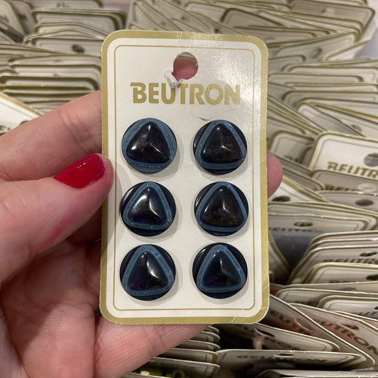 Hand holding a tray of black heart-shaped objects with 'BEUTRON' branding.