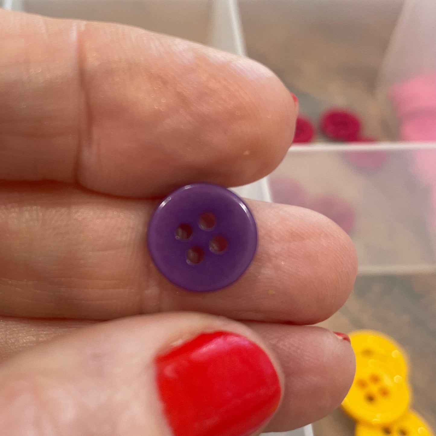 Hand holding a purple button with a blurred background of colorful buttons