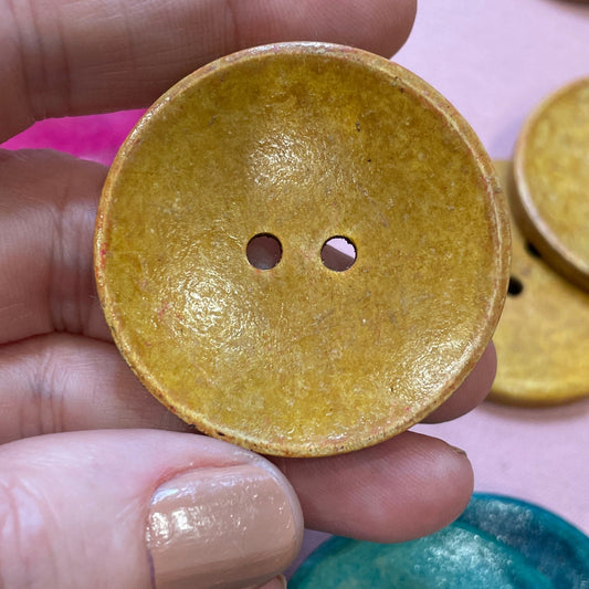 Hand holding a yellow button with other colorful buttons in the background