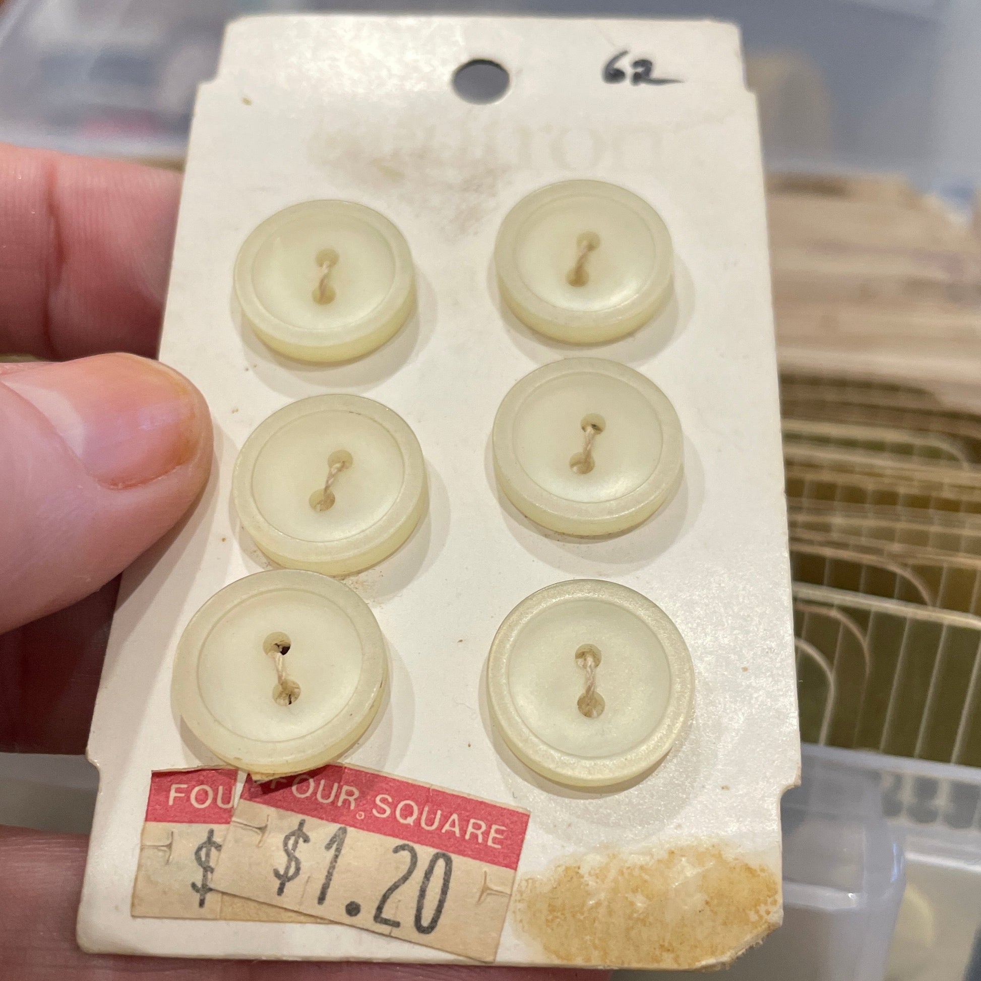 Card with six white buttons held by a hand, with a blurred background
