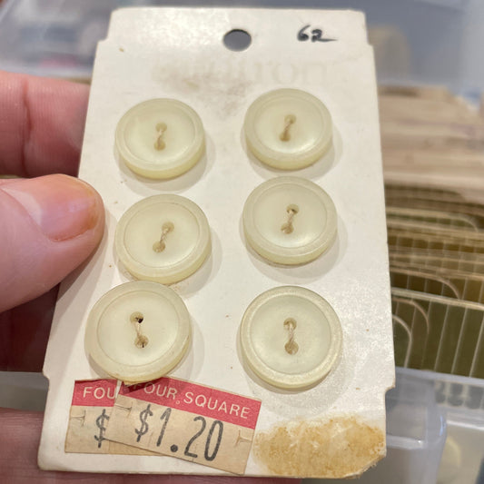 Card with six white buttons held by a hand, with a blurred background