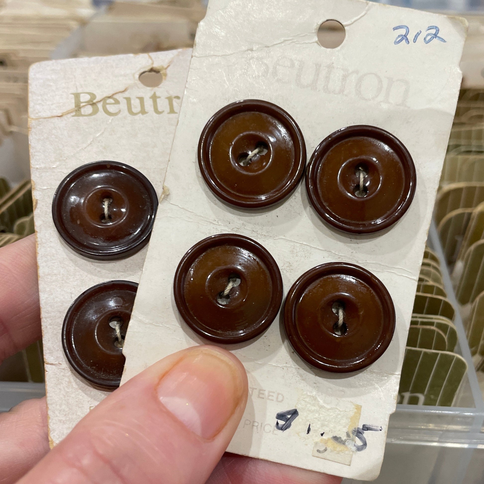 Hand holding a card with brown buttons against a blurred background