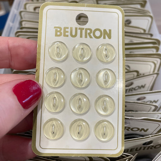 Hand holding a Beutron product packaging with multiple units stacked in the background.
